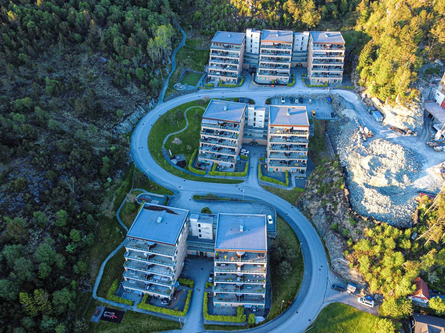 Dronefoto av leilighetsbygg-kompleks med S-vei — kveldsbelysning